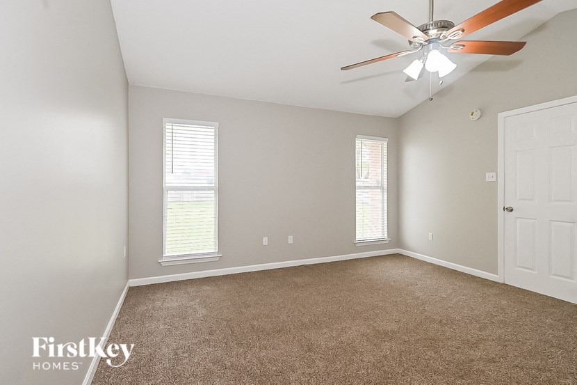 an empty room with a ceiling fan and two windows