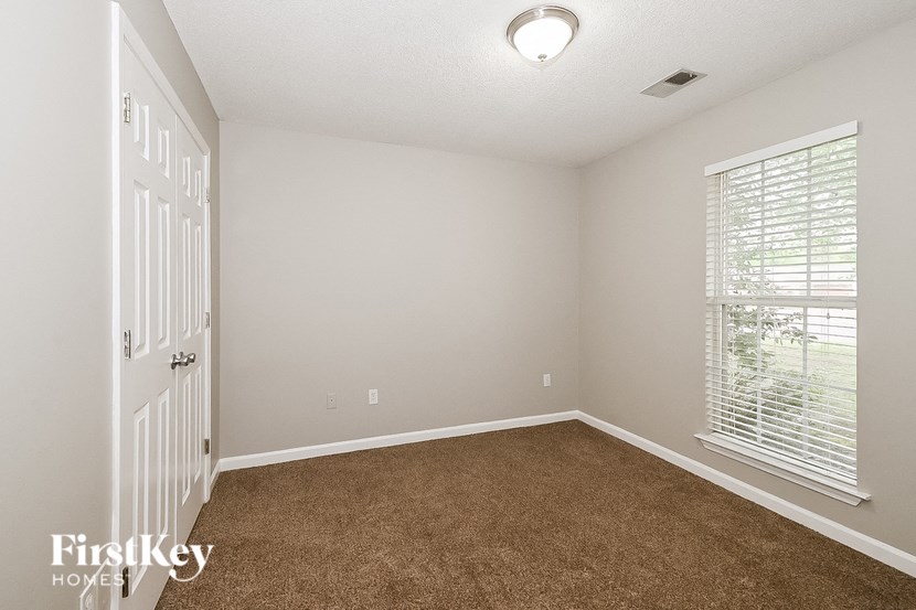 a bedroom with a carpeted floor and a door to a window