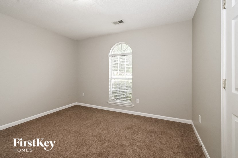an empty bedroom with a large window and carpet