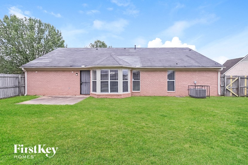 a brick house with a grassy yard and a fence