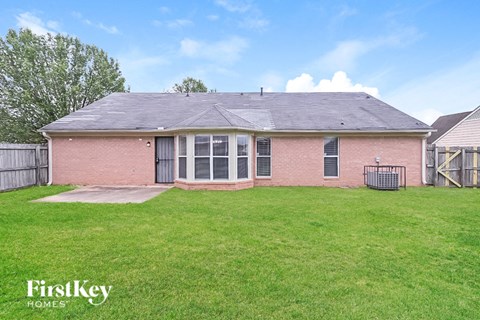 a brick house with a grassy yard and a fence