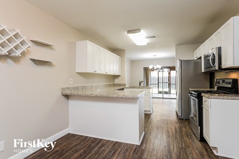 A kitchen with white cabinets and a wooden floor.