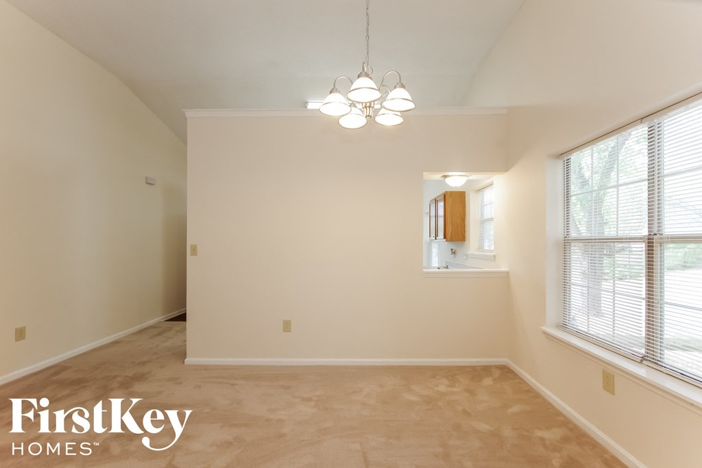 a empty dining room with two windows and a chandelier