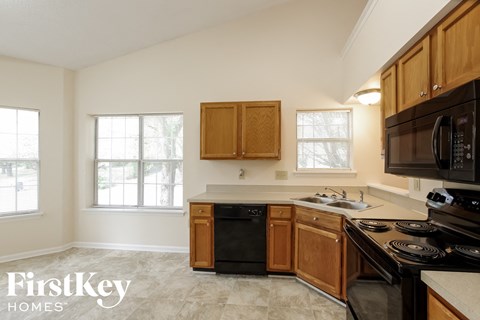 a kitchen with wooden cabinets and black appliances and a sink