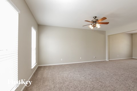 A room with a ceiling fan and carpeted floor.