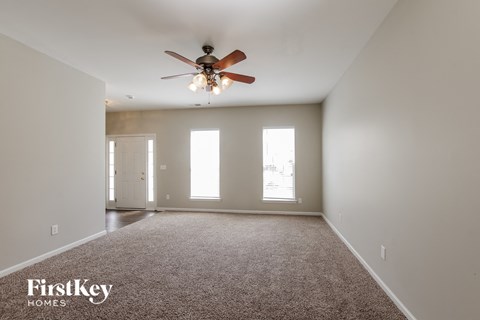 A spacious room with a ceiling fan and carpeted floor.