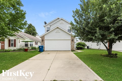 a white house with a driveway and a tree