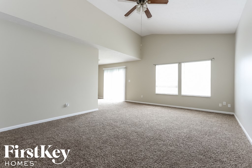 an empty living room with a ceiling fan and a window