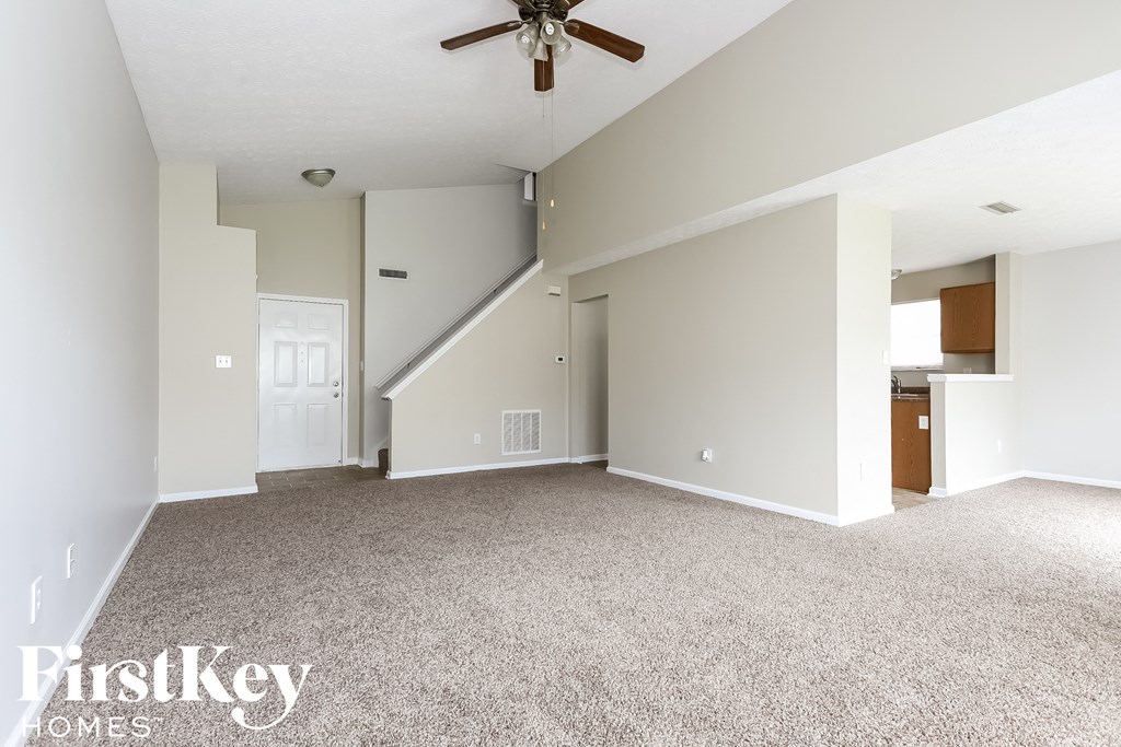 an empty living room with carpet and a ceiling fan