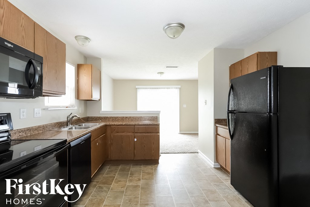 an empty kitchen with black appliances and wooden cabinets