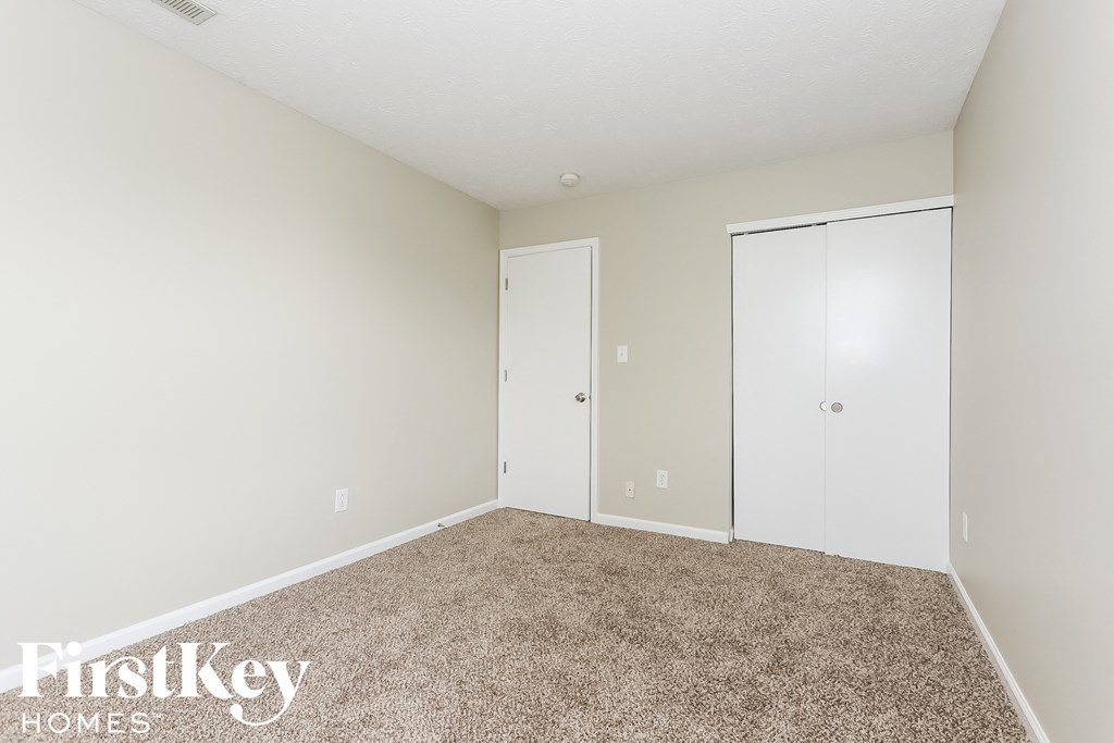 a bedroom with carpet and two closet doors
