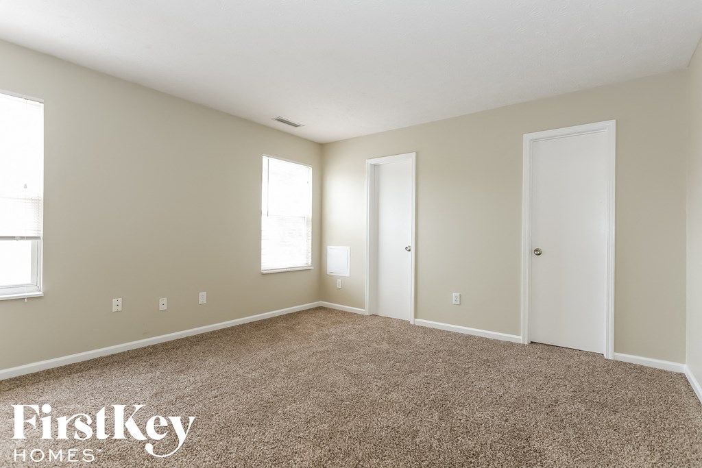 a bedroom with carpet and two doors and a window