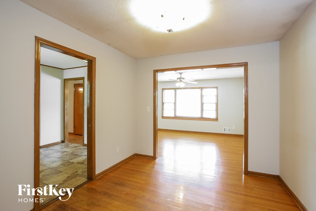 the living room and dining room of an empty house with wood floors and a mirror