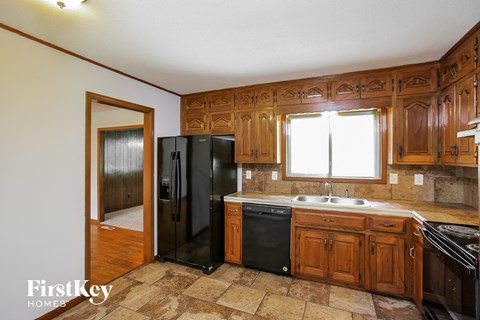 a kitchen with wooden cabinets and a black refrigerator