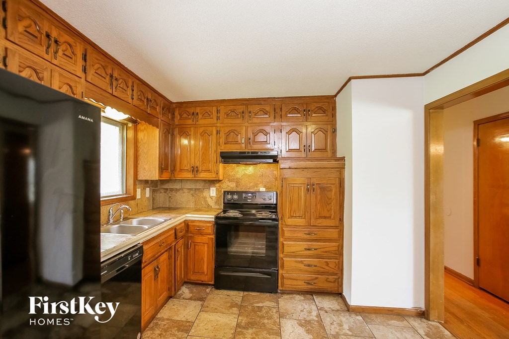 a kitchen with wooden cabinets and black appliances and a sink