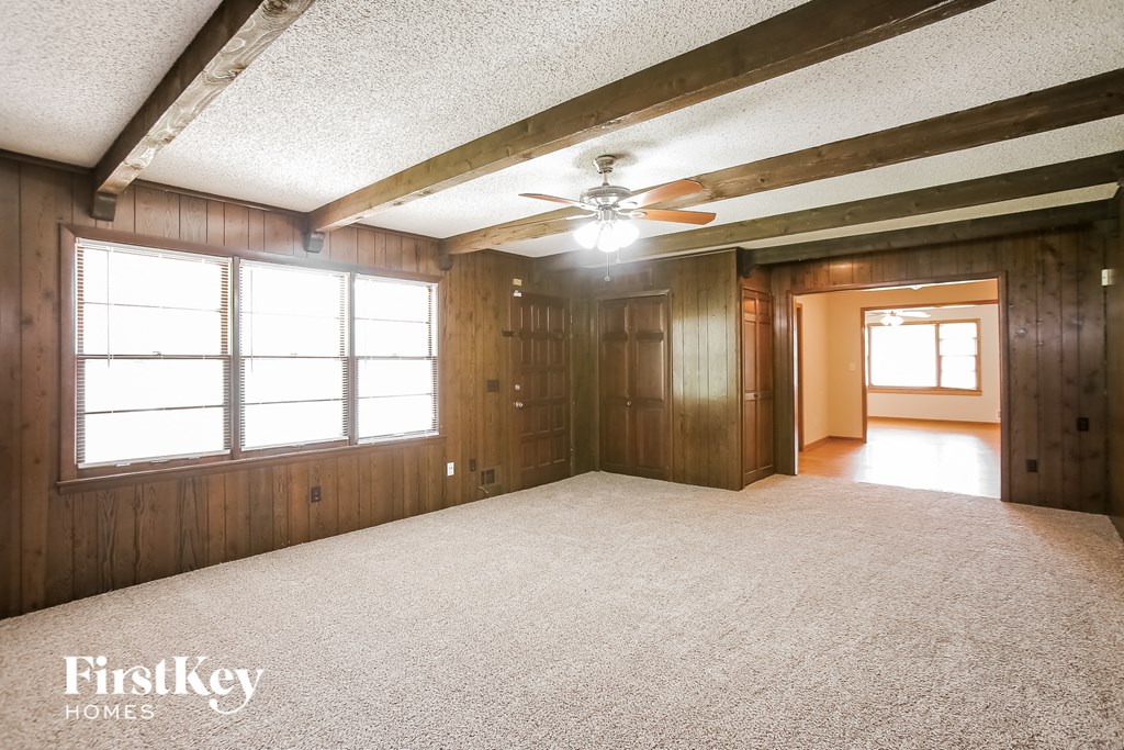 an empty living room with a ceiling fan and a large window