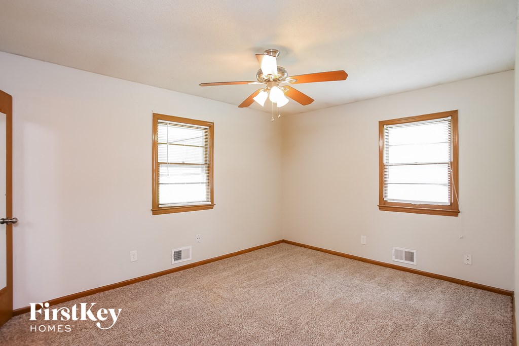 a bedroom with a ceiling fan and two windows