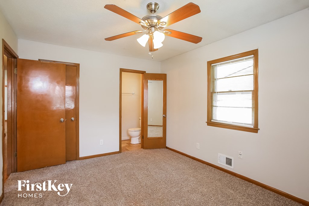 the master bedroom has a ceiling fan and a door to the bathroom