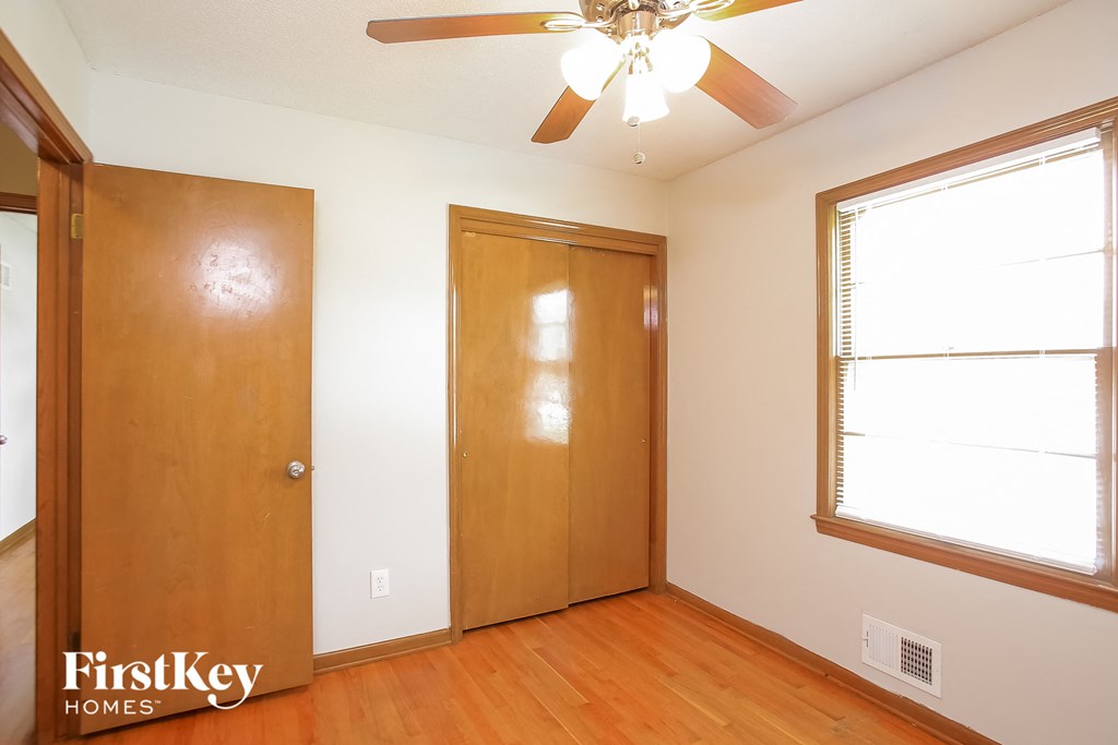 a bedroom with a closet and a window and a ceiling fan