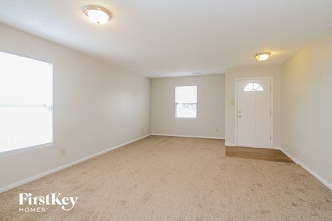 a spacious living room with carpet and a white door