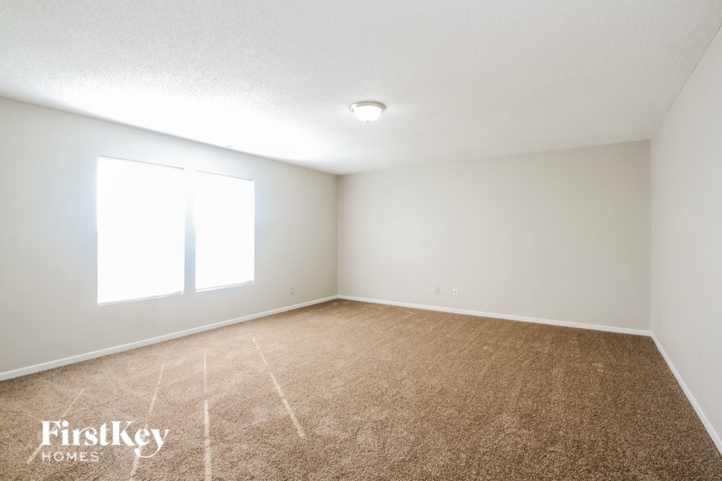 a spacious living room with carpet and a window