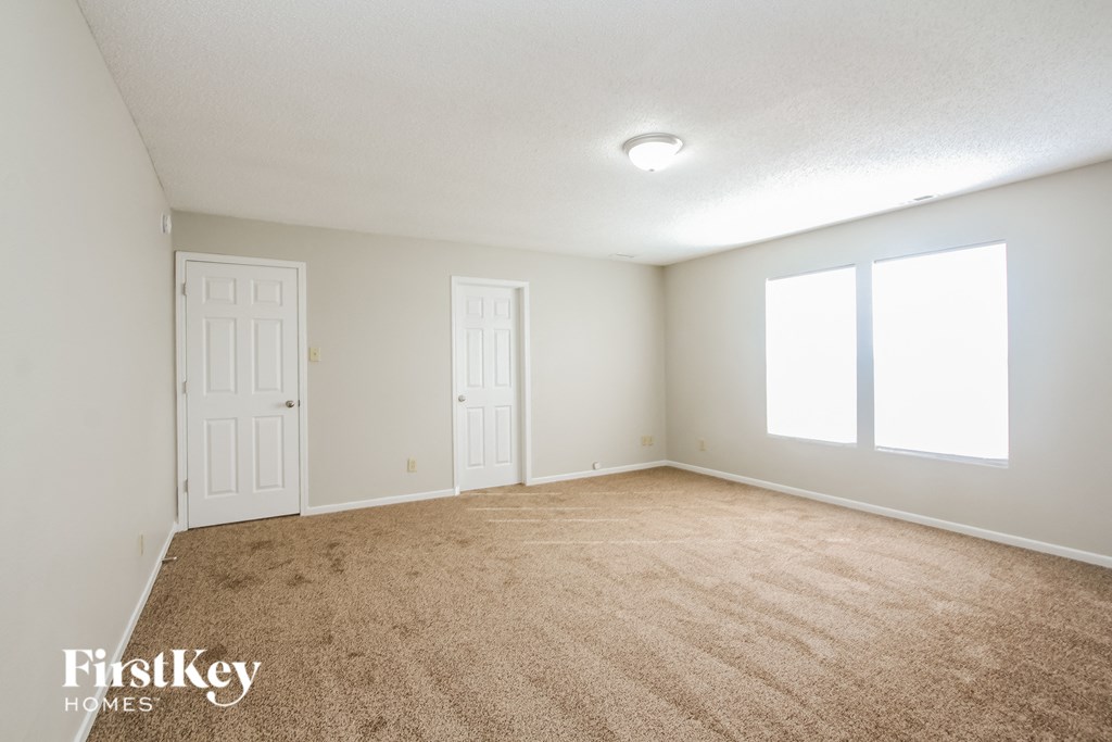 a spacious living room with carpet and two doors
