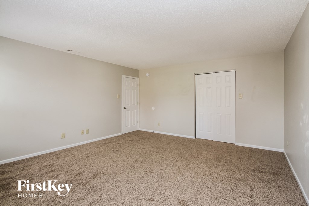 an empty living room with carpet and white doors