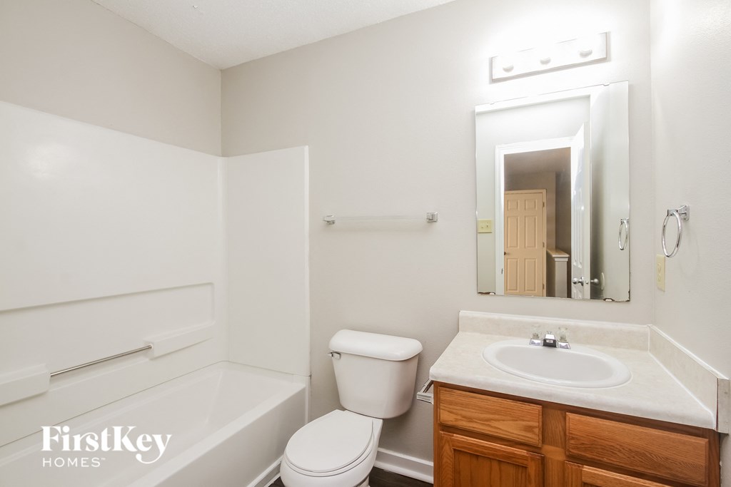 a bathroom with a toilet sink and mirror and a bath tub