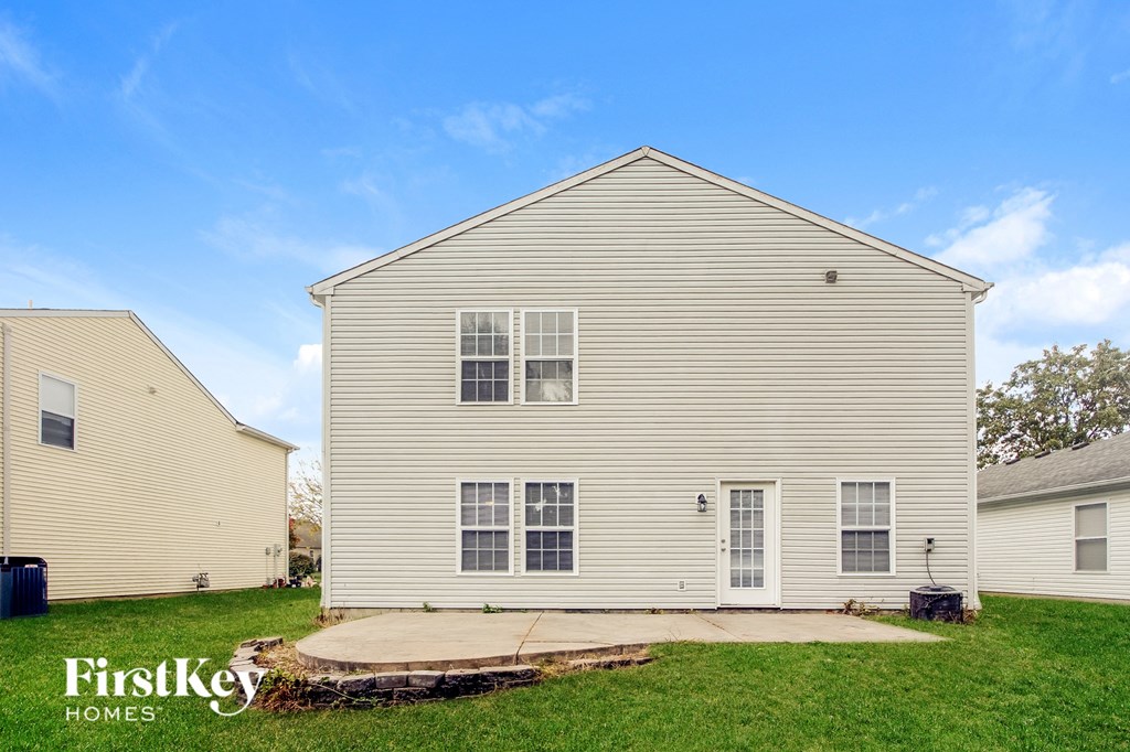 side view of a white house with a sidewalk in the grass