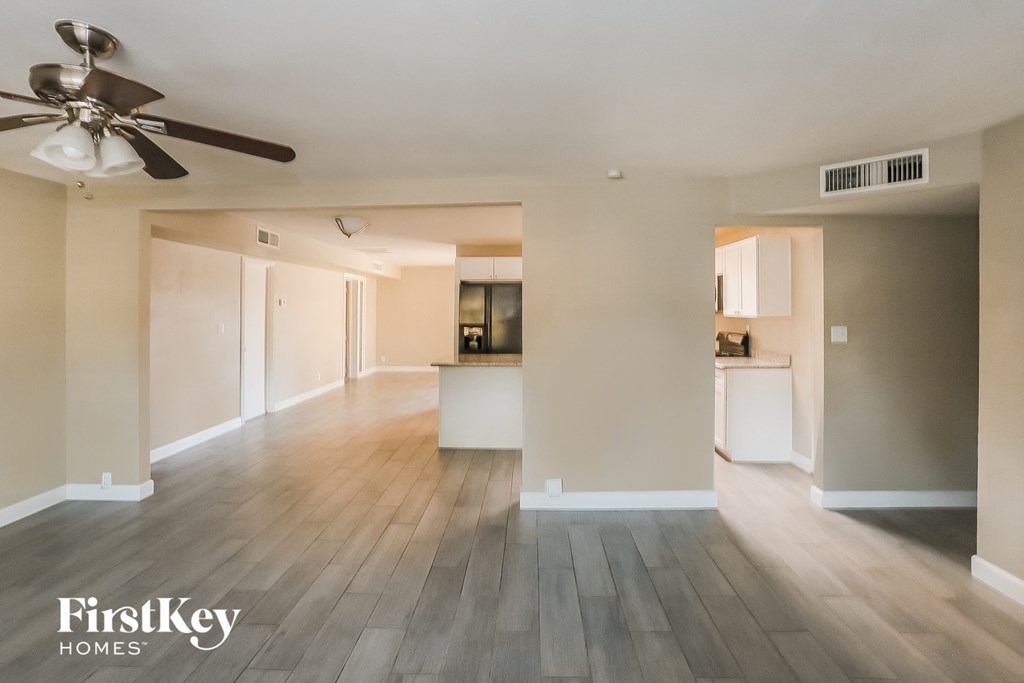 an empty living room with wood floors and a ceiling fan