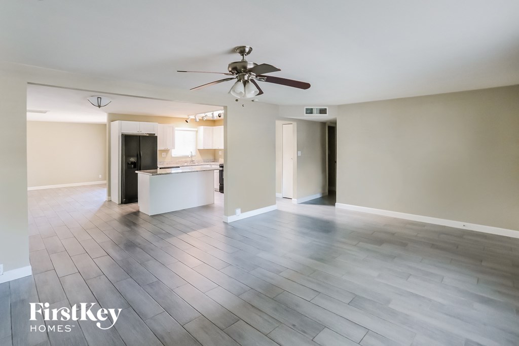 an empty living room with wood floors and a ceiling fan