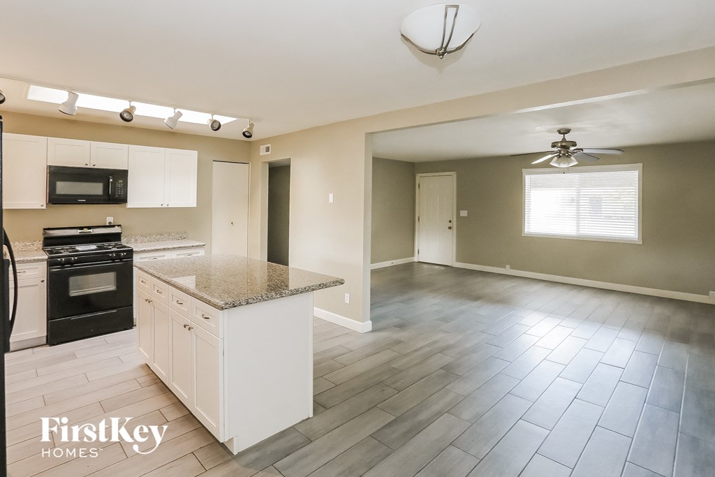 an empty kitchen and living room with white cabinets and a counter top
