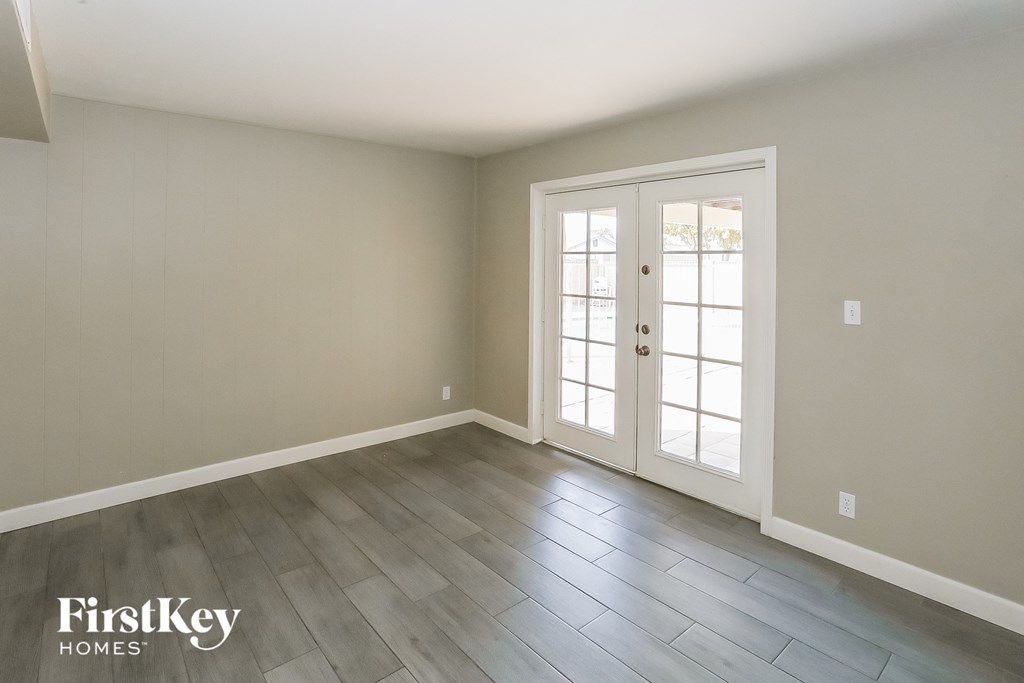 the living room of a house with white doors and wood floors