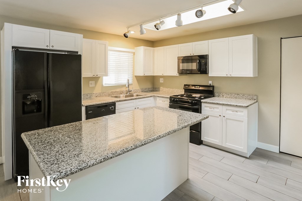 a kitchen with white cabinets and granite counter tops