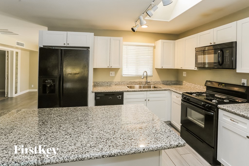a white kitchen with granite counter tops and black appliances