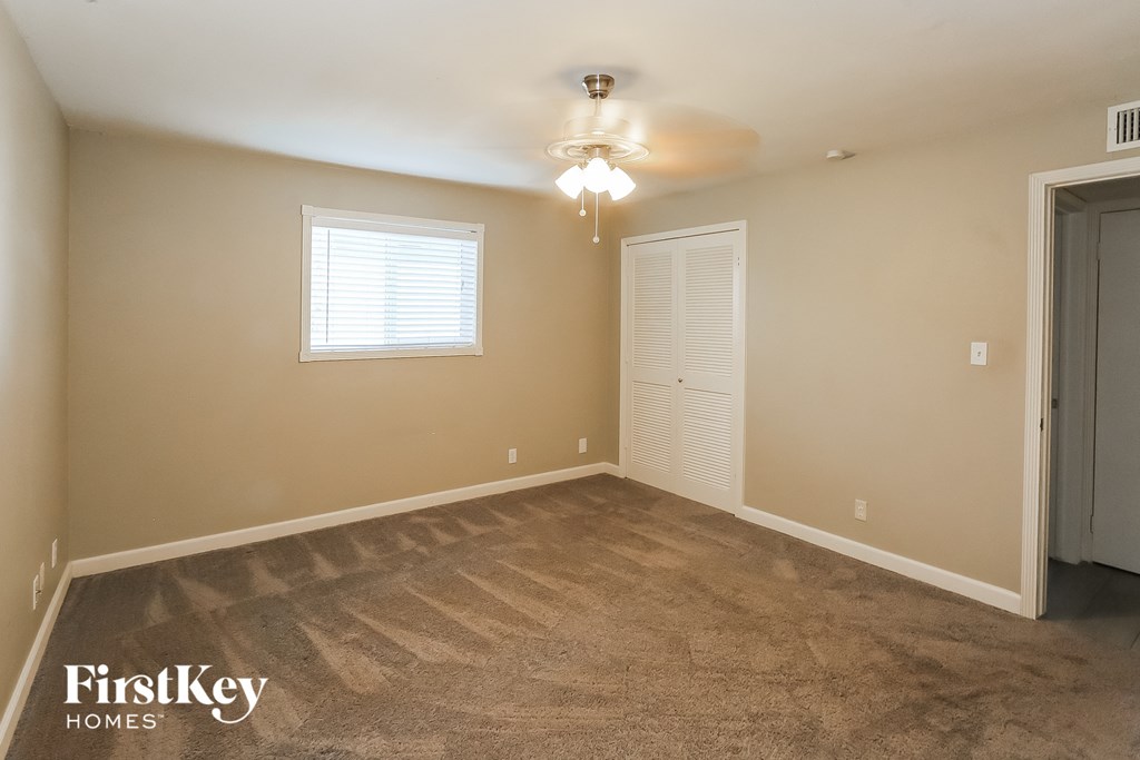 a bedroom with a carpeted floor and a door to a closet
