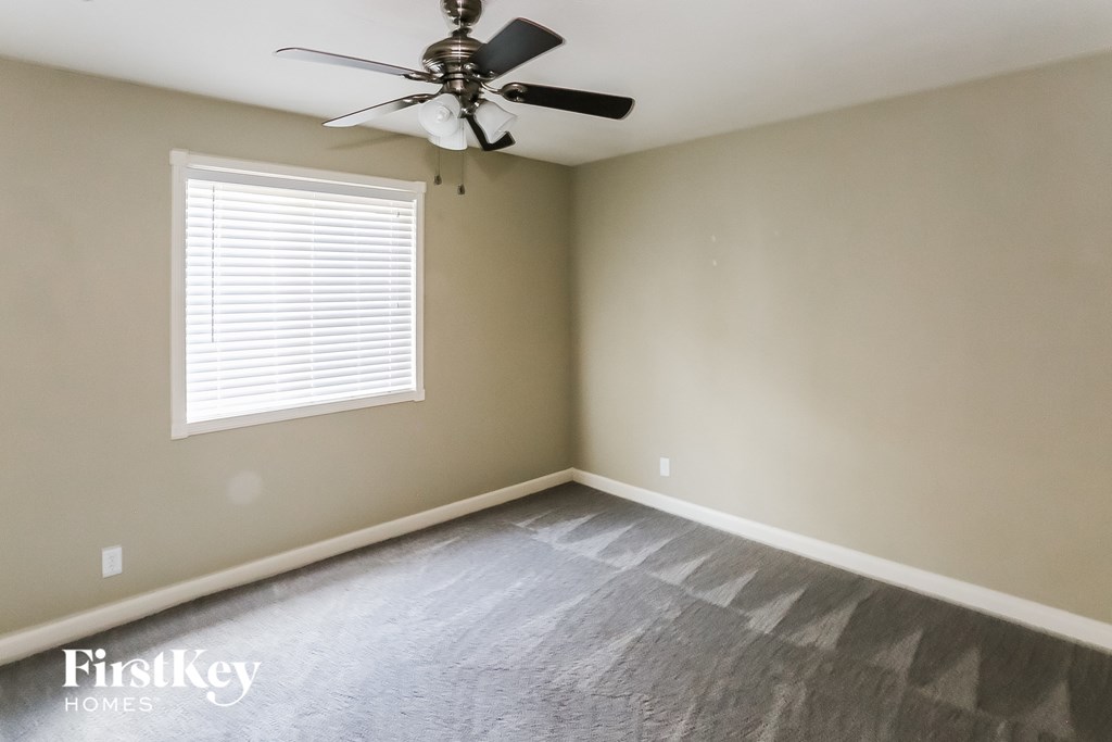 an empty room with a ceiling fan and a window