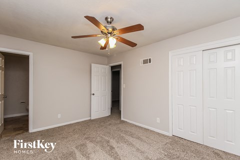 A spacious room with a ceiling fan and carpeted floor.