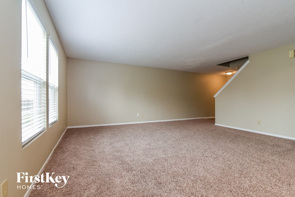 an empty living room with carpet and a large window