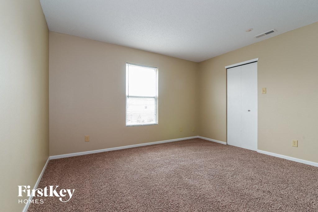 a bedroom with carpet and a window and a door
