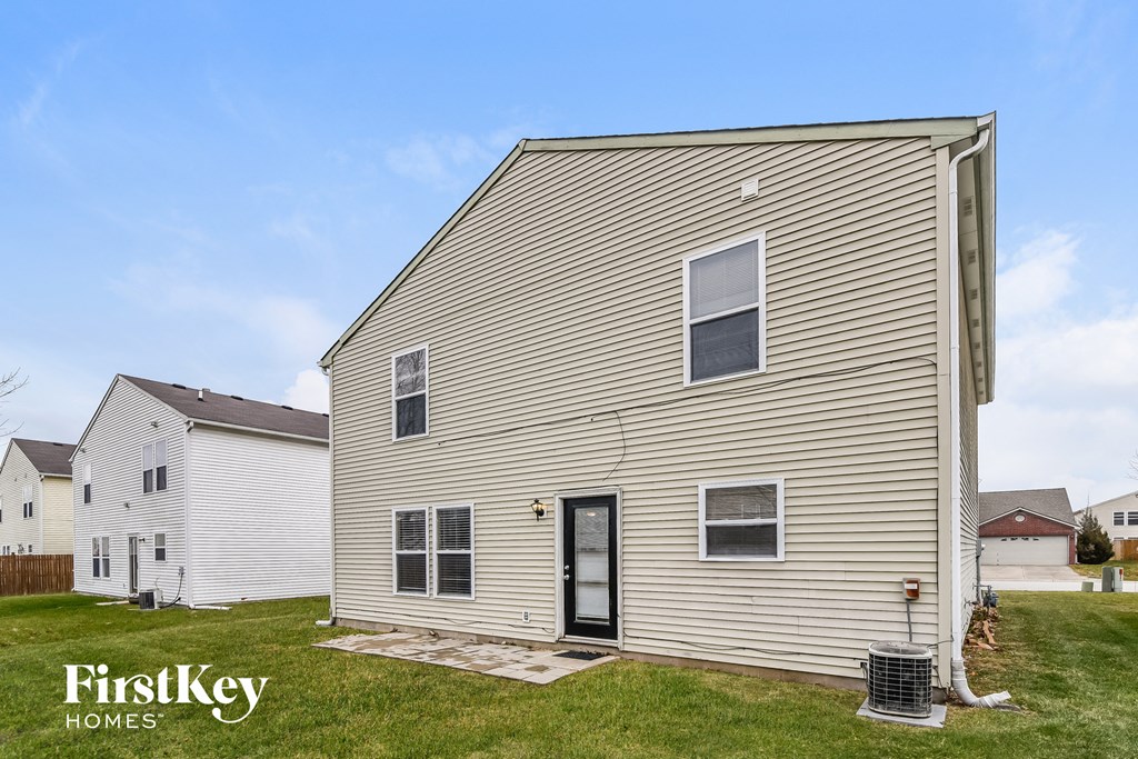 the outside of a house with a yard and a trash can