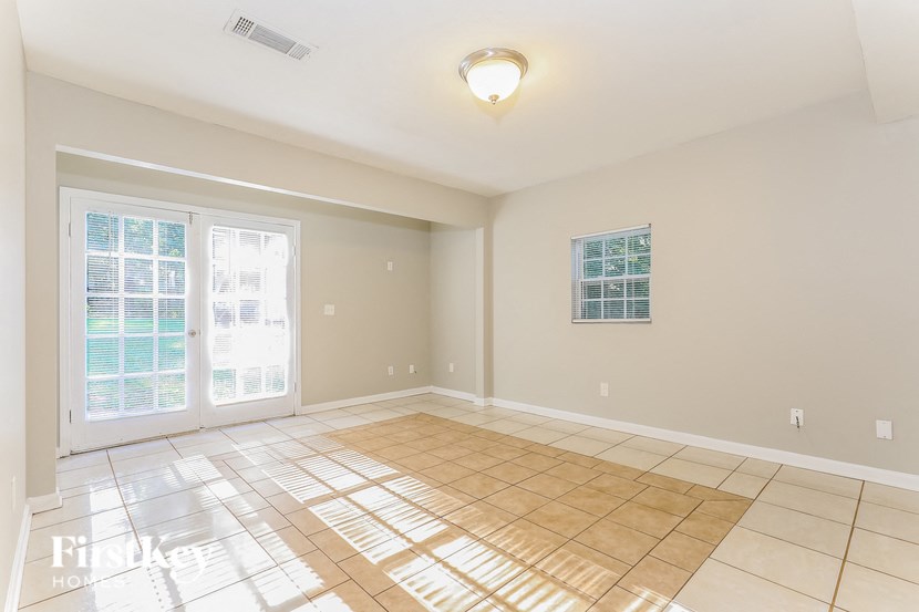 an empty living room with doors and a tiled floor