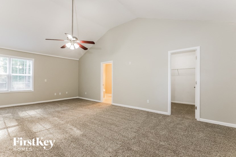 a spacious living room with carpet and a ceiling fan