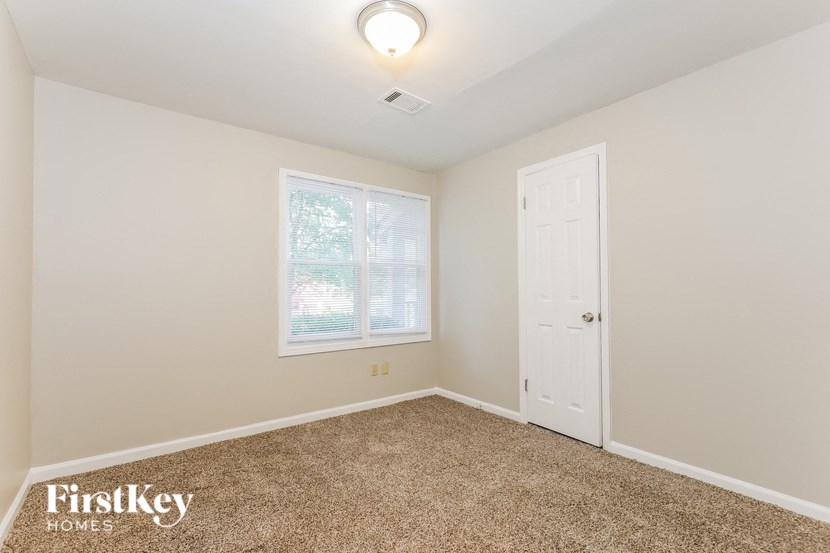 an empty bedroom with a white door and a window