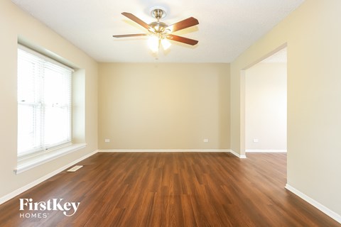 A room with a ceiling fan and wooden flooring.
