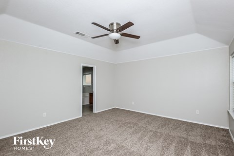 a living room with a ceiling fan and a carpet