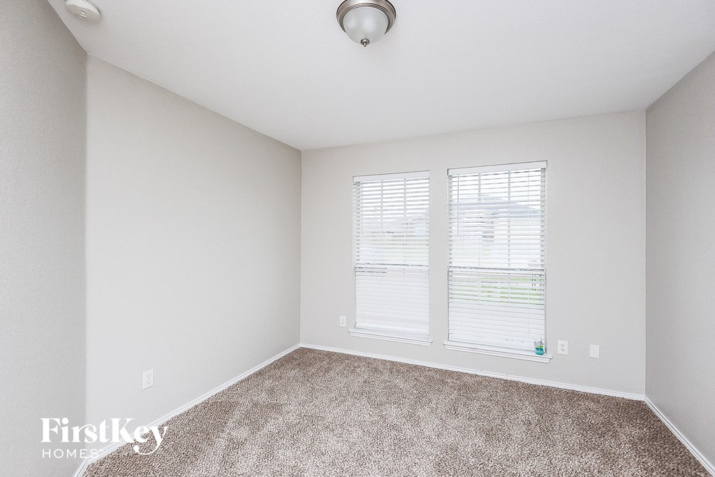 a bedroom with carpet and two windows