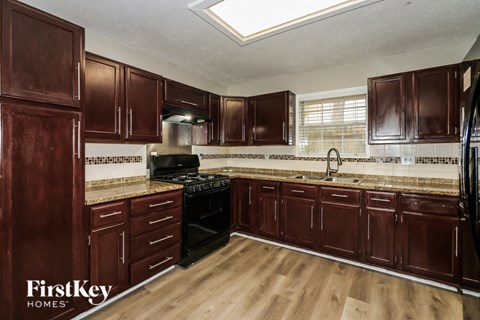 a kitchen with dark wood cabinets and a black stove