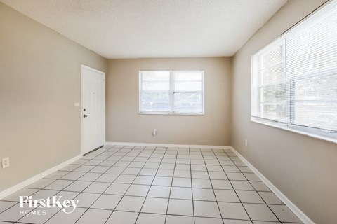 an empty living room with a tiled floor and two windows