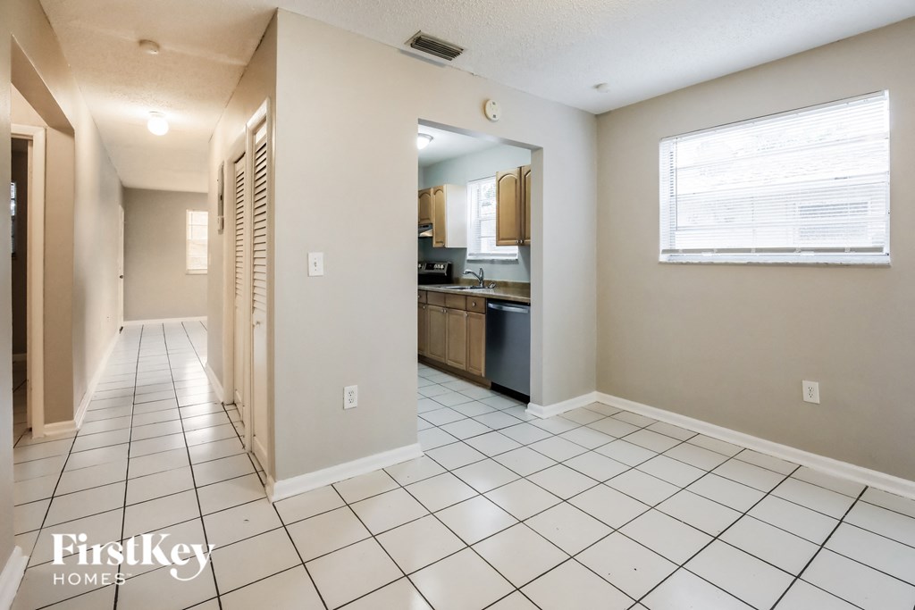 the living room and kitchen of an empty house with a tiled floor
